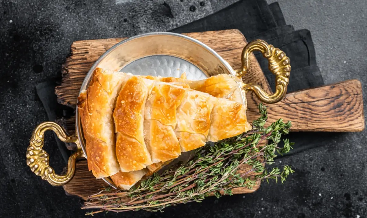 Необходими продукти: кори - 1 пакет точени; яйца - 2 броя; краве масло - 50 г. За плънката: кайма - 500 г микс свинско и телешко; праз - 2 стръка; чубрица - 1 ч.л.; червен пипер - 1 ч.л.; черен пипер - на вкус; сол. Начин на приготвяне: Запържете в сгорещено олио накълцания праз, добавете каймата и бъркайте, докато и тя се запържи и хубаво се раздроби. Овкусете със сол, черен и червен пипер, чубрица, махнете от котлона и оставете да се охлади. Разбийте яйцата с разтопеното масло. Вземайте по 2 кори и ги намазвайте обилно с яйчената смес. В единия край разпределете плънка, завийте на руло и подреждайте така приготвените рула в намазнена тава на охлюв. Отгоре намажете или полейте с останалото от яйчната смес и сложете витата баница с праз и кайма да се изпече в предварително загряна умерена фурна до златисто.